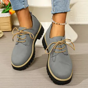Detail view of grey lace-up chunky Oxford shoes with thick black lug soles on a model.