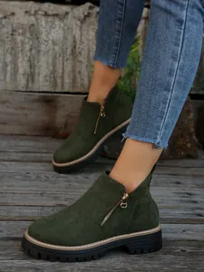 Detail view of stylish dark green suede Martin boots with side zipper and chunky sole