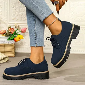Close-up view of navy blue suede lace-up Oxford shoes featuring thick platform lug soles.