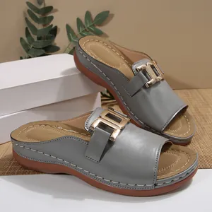 Detailed close-up view of grey women's platform slides with elegant gold metal buckles.