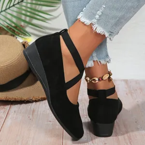 Close-up of black suede pointed-toe wedge shoes with elegant cross-straps