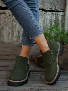 Close-up of women's dark green suede ankle boots with side zippers and chunky soles