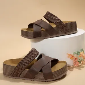 Detailopname van bruine damesplatformsandalen met gekruiste en gevlochten bandjes
