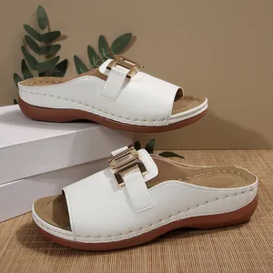 Side view of white wedge slides showing gold buckle and decorative stitching details