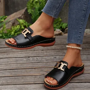 Detailed view of women's black platform wedge slides with stylish gold buckle accents.