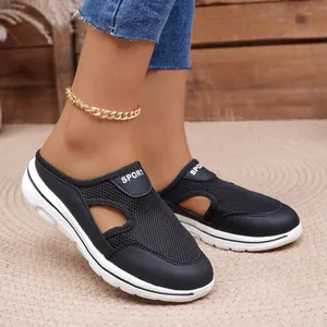 Side view of black mesh mules with white thick soles and sport text detail
