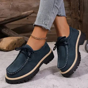 Gros plan de mocassins compensés en daim bleu marine avec surpiqûres blanches.