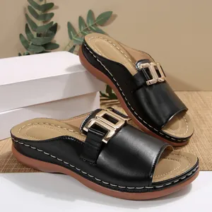 Elegant detail of women's black wedge slides featuring a stylish golden metal buckle