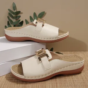Elegant cream-colored wedge slides with decorative gold metal buckle and open toe.