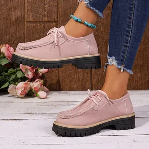 Gros plan de mocassins à plateforme en daim rose portés avec un jean dans un décor rustique