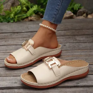 Detail view of stylish beige open-toe wedge sandals with a decorative gold metal buckle.