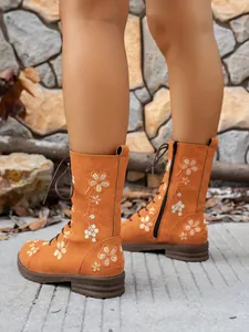 Detailed view of women's orange embroidered mid-calf boots with elegant floral patterns
