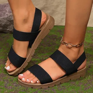 Primo piano di sandali neri da donna con cinturini elastici e comode suole kaki spesse.