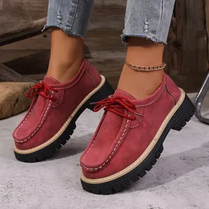 Détail de mocassins à plateforme en daim bordeaux élégants avec lacets rouges portés par pied