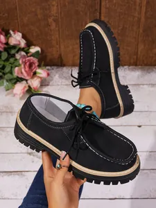 Vue détaillée de mocassins à plateforme noirs avec semelle épaisse et couture blanche