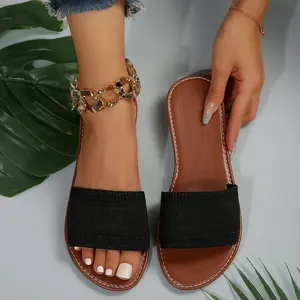 Vista detallada de sandalias planas para mujer con tira negra y plantilla marrón