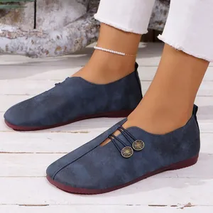 Detalle de mocasines de ante azul marino con botones y suela blanda puestos en los pies