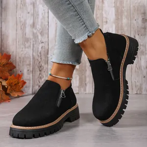 Close-up of black suede ankle boots featuring a side zipper and chunky lug sole design
