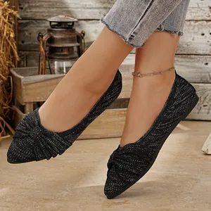 Nahaufnahme von schwarzen, glitzernden spitzen Ballerinas mit elegantem Schleifenknoten am Fuß