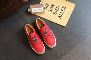 Gros plan de mocassins décontractés rouges avec perforations et sangle rayée.
