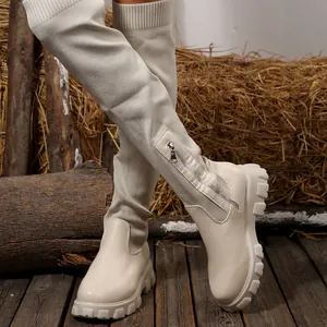 Detailed view of beige knit thigh-high boots featuring a side zipper and chunky lug sole