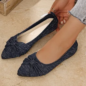 Detailansicht von blauen, funkelnden spitzen Ballerinas mit elegantem Knotendetail am Schuh.