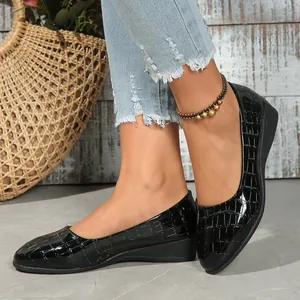 High-quality close-up of black patent leather wedge shoes with crocodile embossed texture