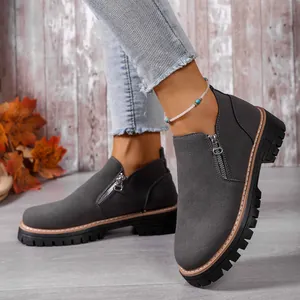 Close-up of grey suede ankle boots featuring a metallic side zipper and chunky sole.