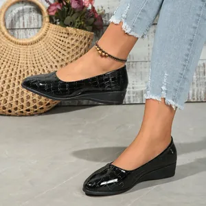 Elegant black patent leather wedge pumps with crocodile texture shown on model's feet