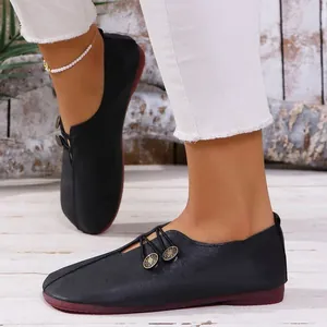 Detalle de los mocasines negros de mujer con botones decorativos y suela blanda