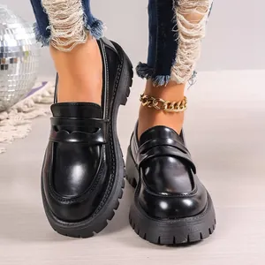 Women's black platform loafers in British style shown on feet in a studio setting
