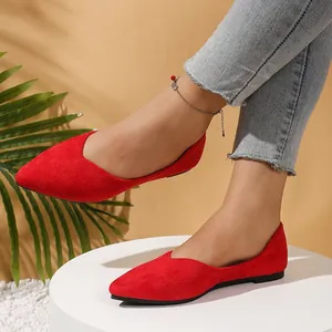 Close-up detail of red pointed-toe suede ballet flats worn by a model in warm light