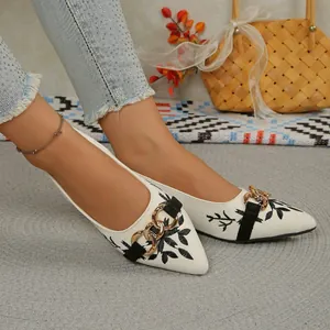 Close-up detail of ethnic white embroidered pointed-toe pumps with gold chain decor