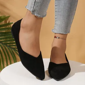 Close-up detail of black pointed-toe suede flats worn with frayed jeans on white platform