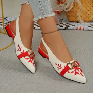 Detailed close-up view of white ethnic sandals with red floral embroidery and gold chain