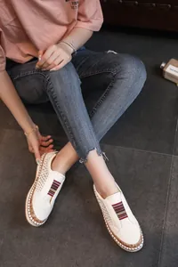 Gros plan sur des mocassins blancs perforés avec un détail de sangle élastique colorée