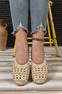 Detailansicht beige ausgeschnittene flache Schuhe mit geometrischen Lasercut-Mustern.