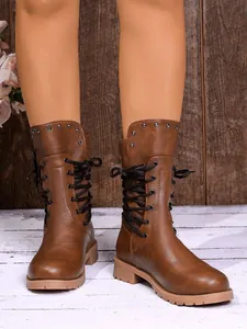 Detailed view of brown faux leather mid-calf boots with side laces and studs