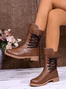 Close-up of brown mid-calf women boots with crisscross lacing and stud details for 2025