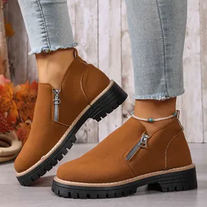 Close-up of stylish brown suede ankle boots with side zipper and thick black lug sole.
