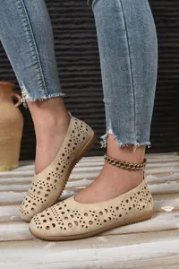 Nahaufnahme von beigefarbenen Damen-Loafern mit schicken Lochmustern und Details