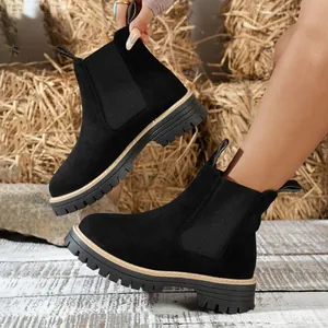 Vista detallada de botines Chelsea de ante negro con suela de lengüeta resistente.