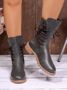 Detailed view of women's grey mid-calf boots featuring stud accents and brown laces.