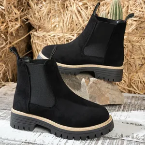 Vista lateral detallada de botines Chelsea de ante negro con suelas de plataforma gruesas