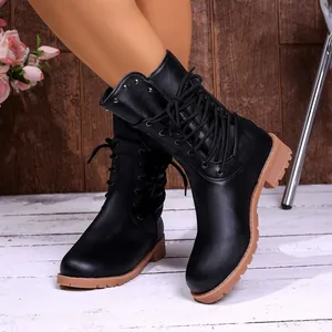 Close-up of black lace-up combat boots with tan chunky soles and stud details