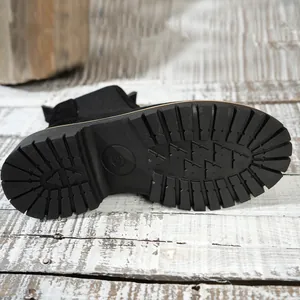 Detailed macro view of the thick anti-slip rubber outsole on black suede ankle boots