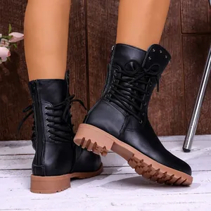 Close-up of black lace-up combat boots with tan lug soles and side zipper detail