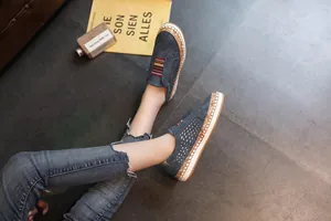 Baskets bleues perforées pour femmes avec détail élastique rayé sur sol en pierre.