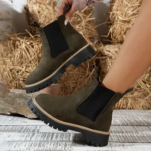Detailed view of dark green suede Chelsea boots featuring chunky black block heels and lug soles