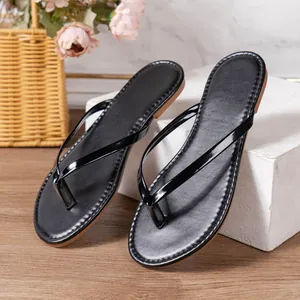 Detail van zwarte glanzende slippers met elegant bandje en doorgestikt voetbed